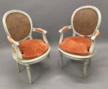 A pair of late 19th/early 20th century caned painted open armchairs Each shaped moulded caned oval