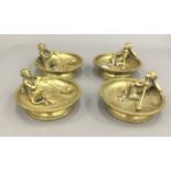 A set of four late 19th/early 20th century brass ashtrays each mounted with a bronze monkey smoking