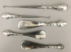 Three silver ended shoehorns and two silver ended boot hooks