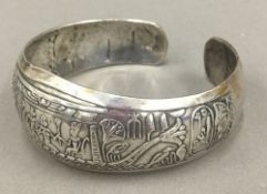 A silver bangle depicting an Egyptian scene