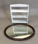 An oval framed wall glass and a set of painted shelves