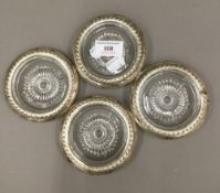 A set of four white metal mounted glass coasters