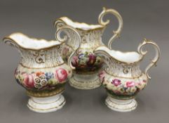 A graduated set of three 19th century floral hand painted porcelain jugs