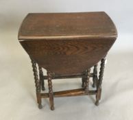 An early 20th century oak barley twist drop flap table,