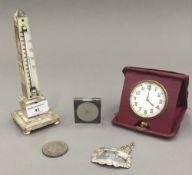 A mother-of-pearl thermometer, a travelling clock, a silver decanter label, etc.