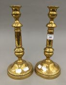 A pair of engraved brass candlesticks