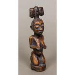 An African carved wooden tribal figure, possibly Yoruba Formed as a naked female kneeling,