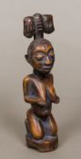 An African carved wooden tribal figure, possibly Yoruba Formed as a naked female kneeling,