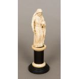 An 18th/19th century carved ivory model of a saint Dressed in robes holding a book,