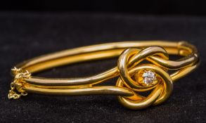 A 15 ct gold diamond set hinged bangle form bracelet The central knot section set with a central