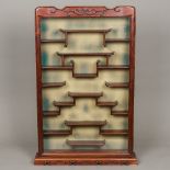 A Chinese glazed carved hardwood netsuke cabinet The hinged door with carved shaped top enclosing