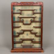 A Chinese glazed carved hardwood netsuke cabinet The hinged door with carved shaped top enclosing