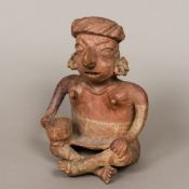 A Pre-Columbian Colima red slip pottery figure Modelled as a seated woman holding a drinking vessel.