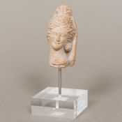 An antique terracotta fragment Worked as a female head wearing a headdress, on perspex plinth base.