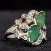 A white gold and platinum diamond and emerald set ring Of pierced scrolling form. 2 cm high.