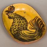 A slip decorated pottery dish Of rounded rectangular form, worked with a cockerel. 42.5 cm wide.