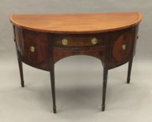 A 19th century satinwood banded and inlaid mahogany demi-lune sideboard/serving table Fitted with a