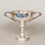 A George V silver twin handled trophy cup Of pedestal form, with twin angular handles,