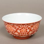 A Chinese porcelain bowl Decorated with lotus strapwork on a red ground,