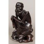 A late 19th century Chinese carved hardwood figure Modelled as an emaciated male seated on a