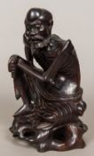 A late 19th century Chinese carved hardwood figure Modelled as an emaciated male seated on a