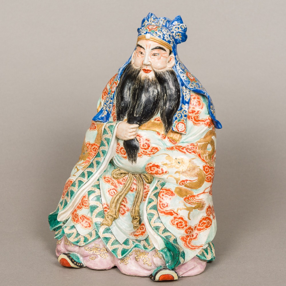 A Japanese Meiji period porcelain figure Modelled as a seated bearded gentleman wearing an