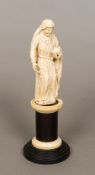 An 18th/19th century carved ivory model of a saint Dressed in robes holding a book,