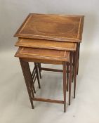 An Edwardian satinwood banded mahogany nest of three tables