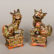 A pair of Chinese antique polychrome and gilt decorated pottery temple lion incense stick holders,