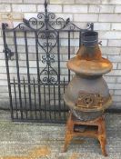 A vintage pot belly log burner and a wrought iron gate