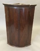 A George III mahogany bow front hanging corner cupboard with painted interior. 67 cm wide.