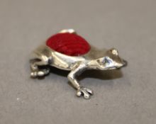 A silver pin cushion formed as a frog