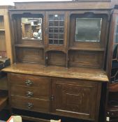 An Arts and Crafts oak sideboard with twin bevelled mirror plate back