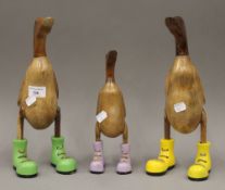 Three models of wooden ducks wearing boots