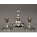 A pair of white metal hand tooled Middle Eastern candlesticks with foliate designs and a larger