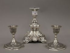 A pair of white metal hand tooled Middle Eastern candlesticks with foliate designs and a larger