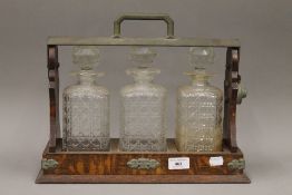An oak three bottle tantalus with cut glass decanters