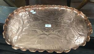 An Arts and Crafts embossed copper tray, worked with organic floral scrolls within a shaped rim,