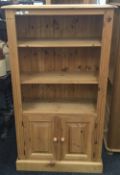 A modern pine bookcase with cupboard doors below