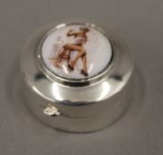 A silver pill box set with a scantily clad female