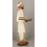 An early 20th century painted figural dumb waiter Typically modelled holding a brass tray.