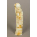 A Chinese carved celadon jade model of Shou Lao Typically modelled holding a fruit and a staff,