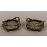 A pair of Chinese cast bronze censers Each of squat circular form with twin handles,