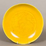 A Chinese porcelain dished plate Decorate with a dragon amongst stylised clouds on a yellow ground,