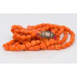 A Chinese carved coral bead three strand necklace Set with a silver clasp,