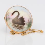 A 9 ct gold framed porcelain brooch Painted with a black swan. 2.75 cm.