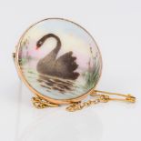 A 9 ct gold framed porcelain brooch Painted with a black swan. 2.75 cm.