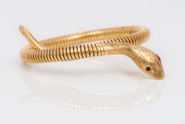 A 9 ct gold steel sprung bangle bracelet Modelled as a serpent with ruby set eyes.