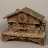 A late 19th century Black Forest carved wooden music box/clock Formed as an Alpine Chalet.