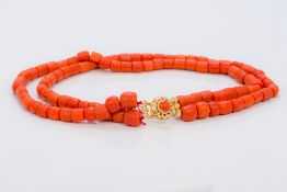 A two strand coral bead necklace Set with a coral cabochon mounted pierced gold clasp. 39.